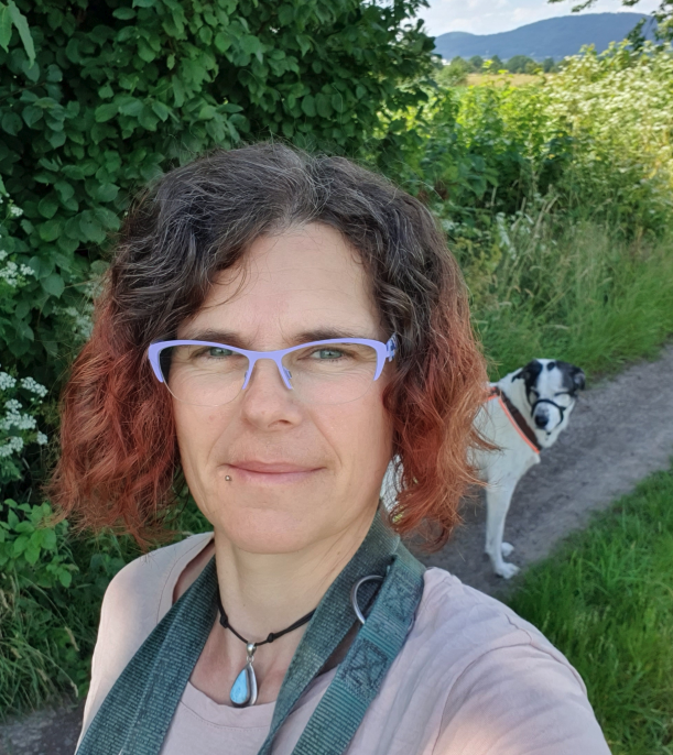 Frau mit Hund im Hintergrund in Natur