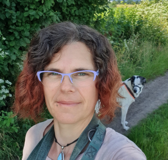 Frau mit Hund im Hintergrund in Natur